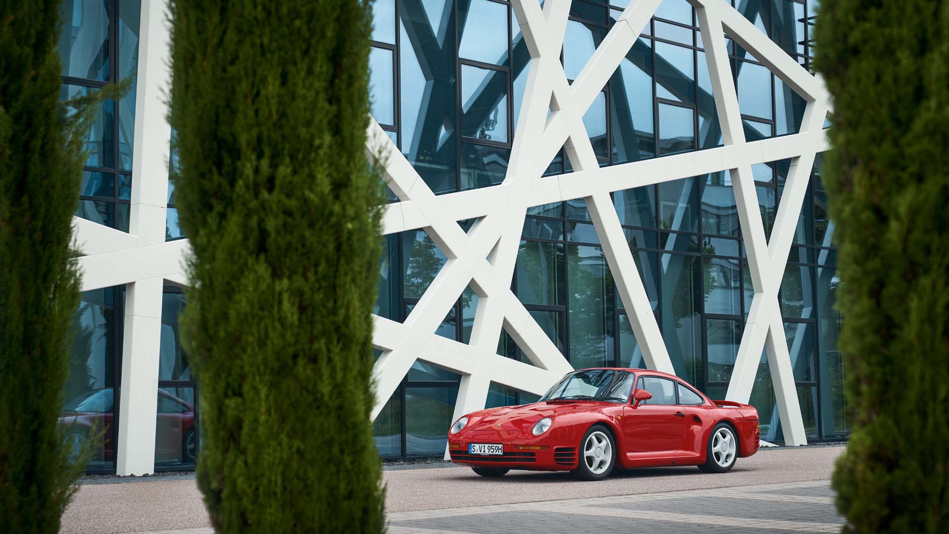 A pristine Porsche 959 supercar on a scenic road