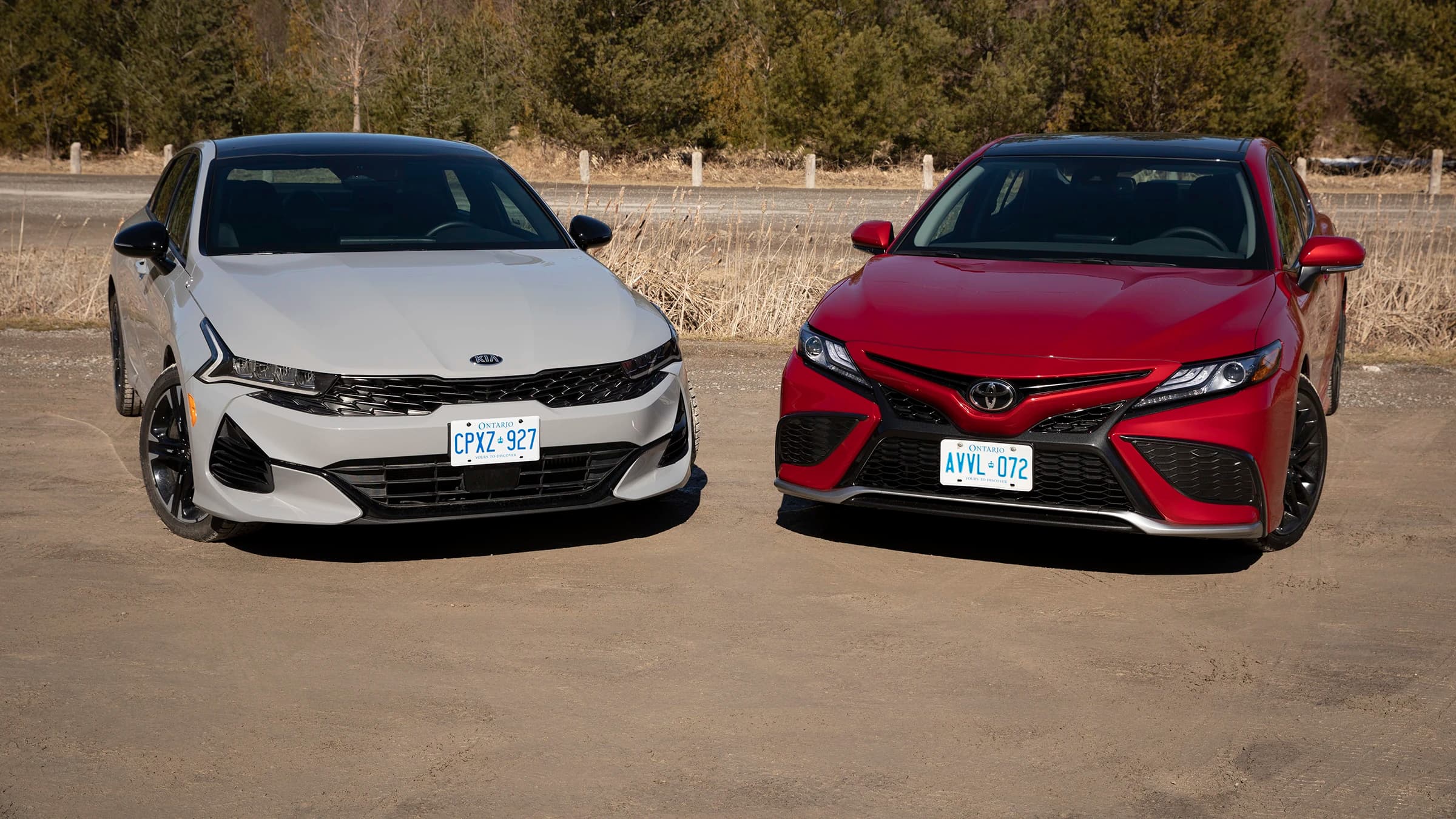 A 2026 Toyota Camry and Kia K5 parked side-by-side on a scenic road
